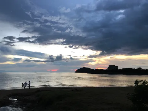 夕暮れの海辺、家族のシルエット
