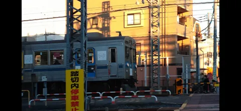 夕暮れの踏切、銀色の車体