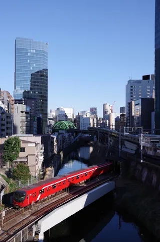 都会の川と赤い列車