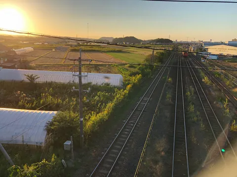 夕暮れ、線路とビニールハウスの道