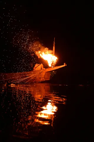 炎と水面が紡ぐ夜の舟影