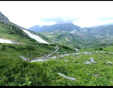 緑の谷を歩む登山客