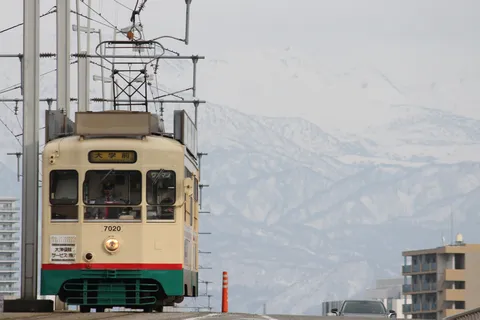 雪山を背に走るレトロな電車