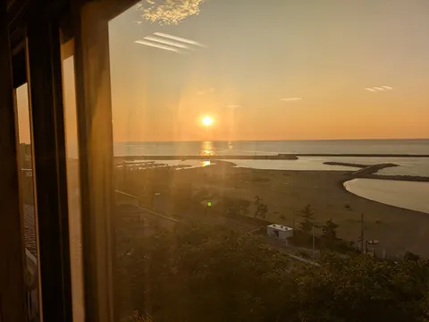 窓越しに映る夕日と海の静けさ
