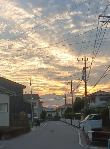 電線が交差する、夕焼けの住宅街