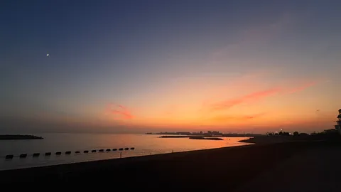 夕暮れの海と月影