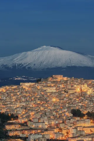 雪化粧の山と光る街のコントラスト