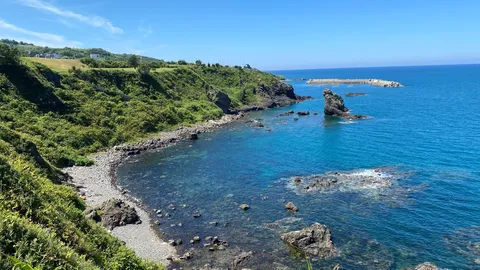 青い海と緑の丘、風の吹き抜ける海岸