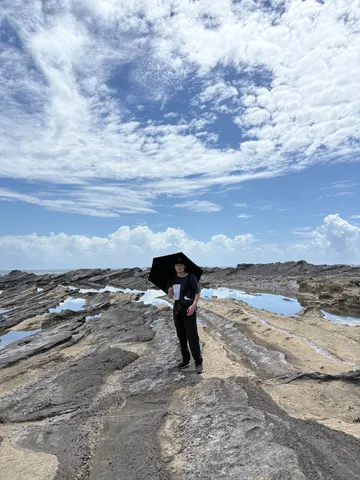 傘と岩場の海辺、波長の雲