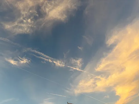 空を彩る飛行機雲と夕焼け