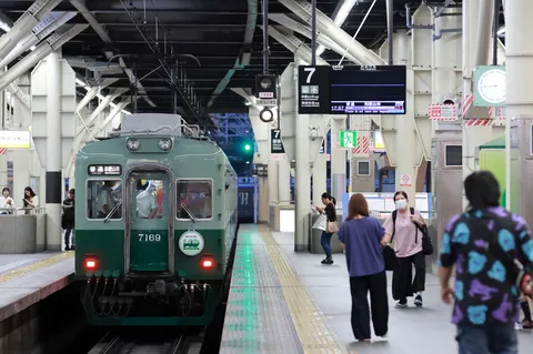 発車を待つ、緑の電車と人々