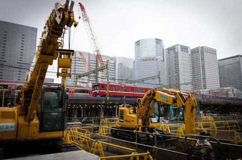 都会の建築現場と赤い列車