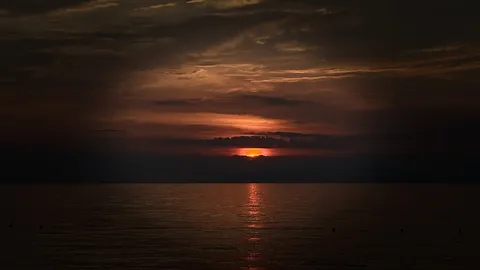 沈みゆく夕陽、水面の残照