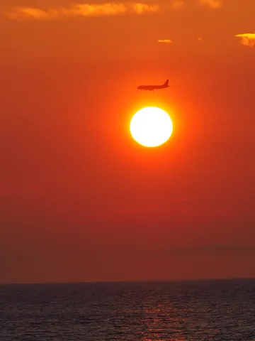 夕日と飛行機、水平線のコントラスト