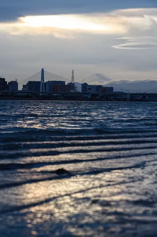 薄暮の水辺、橋の向こうにそびえる山