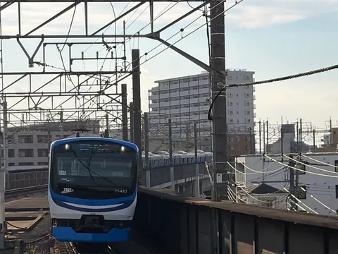 青と白の電車、都会の空へ