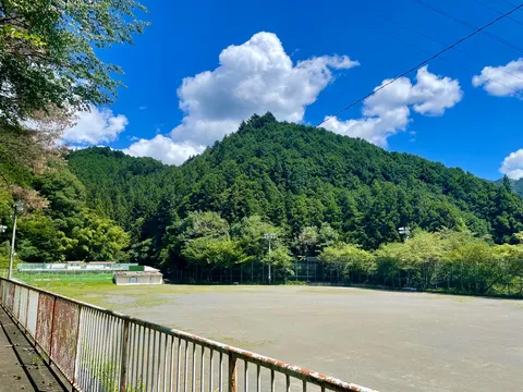 緑深き山の麓、静かなグラウンド