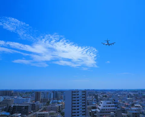 青空に映る旅客機、都市の日常