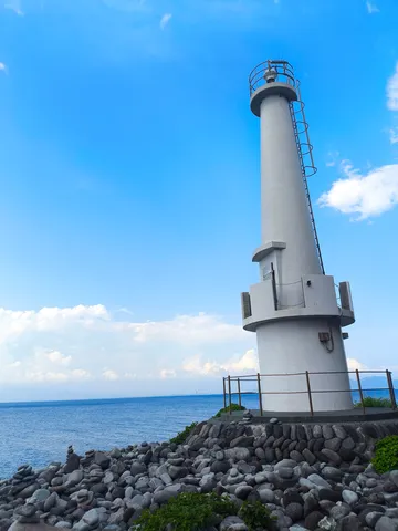 青い空と灯台、石の海岸