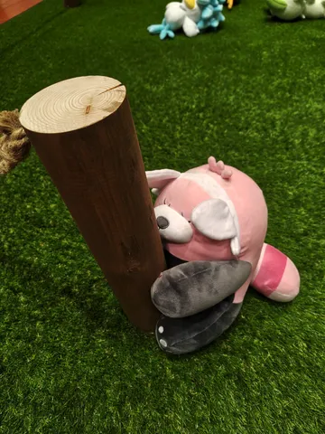丸太と戯れるピンクのぬいぐるみ