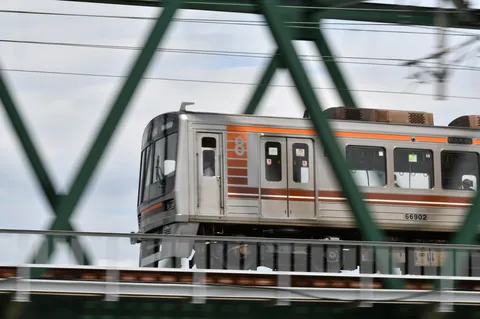 緑の橋梁を渡る銀色の車体