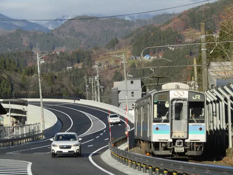 山間のカーブを走る列車と車