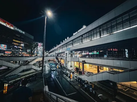 雨夜を走る駅前の光