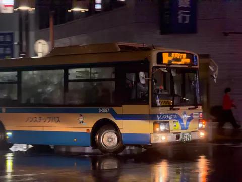 雨夜の街を走るバスの光