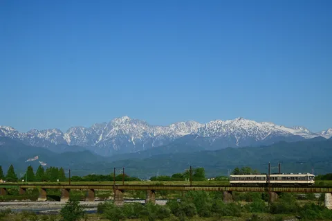 鉄橋をゆく列車と雪山