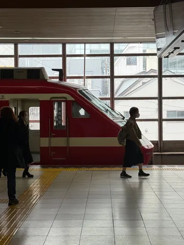 窓辺の赤い列車と行き交う人々