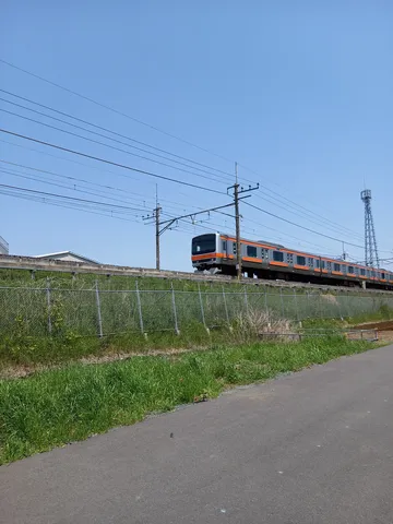 青空とオレンジの電車、風薫る鉄道風景