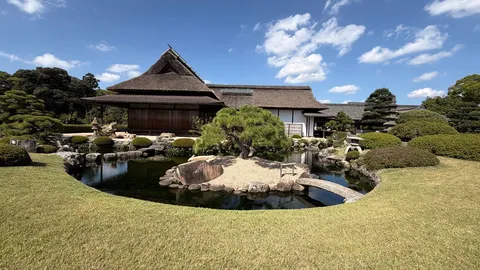 水辺に映る茅葺の館と庭