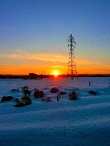 冬の夕暮れ、電波塔と雪原