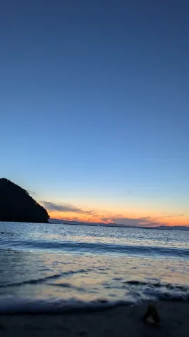 水平線に沈む夕陽、静かな水辺
