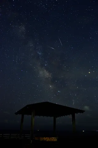 天の川と流れ星、小屋のシルエット