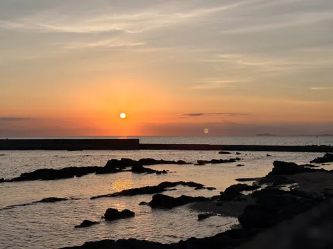 夕暮れの海、静かな水面と岩