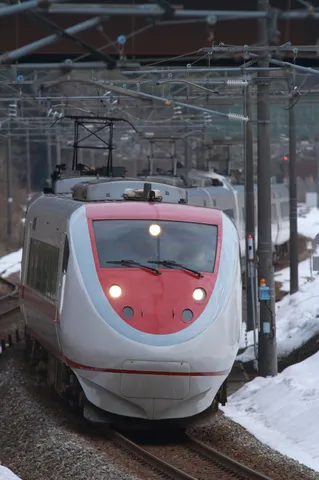 雪の線路を進む白と赤の列車