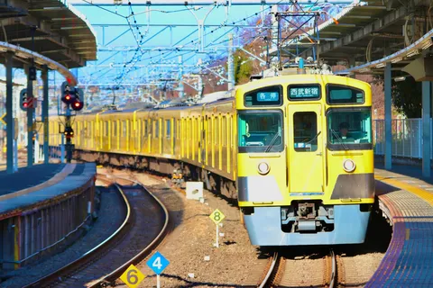 青空の下、駅へ向かう黄色い電車