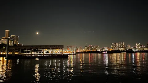 夜の水面に浮かぶ月と灯り