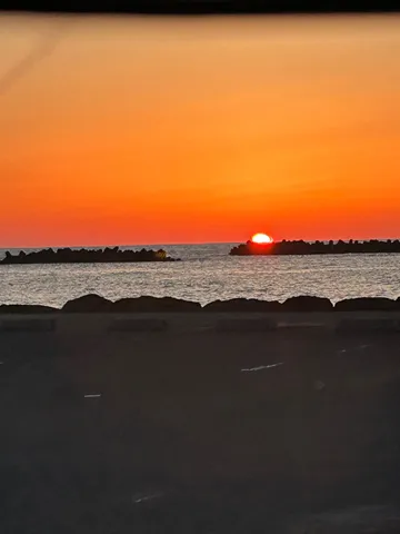 水平線に沈む夕日、静かな波打ち際