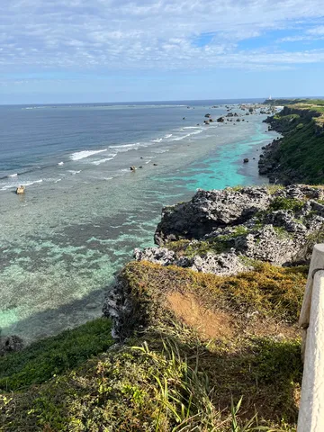 青き岩場と遠い灯台の海岸線