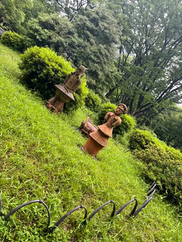 緑の斜面に佇む、素朴な土人形