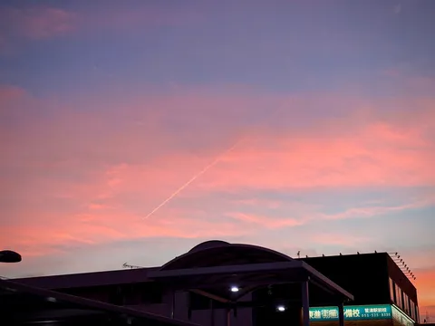 ピンク色の空と飛行機雲、日常のドラマ