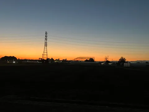 夕暮れの鉄塔とビニールハウス