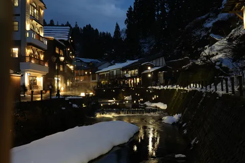 雪夜の灯りが映す川辺の街