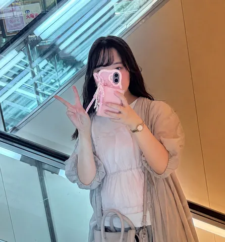 ピンクのスマホとピースサイン