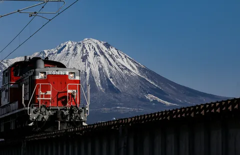 雪化粧の山を背景に疾走する赤い列車