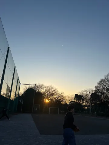 夕暮れのコートでボールを追う