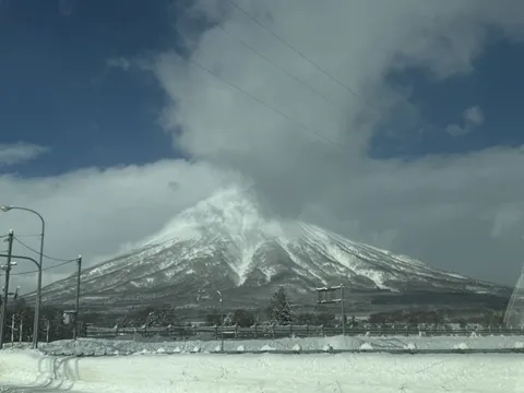 雲をまとう雄大な雪山と電線
