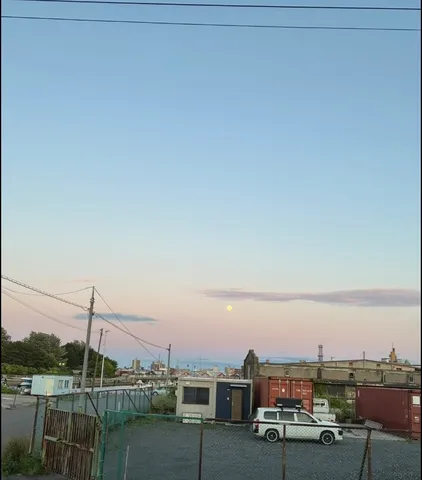夕暮れに浮かぶ月と都会の風景